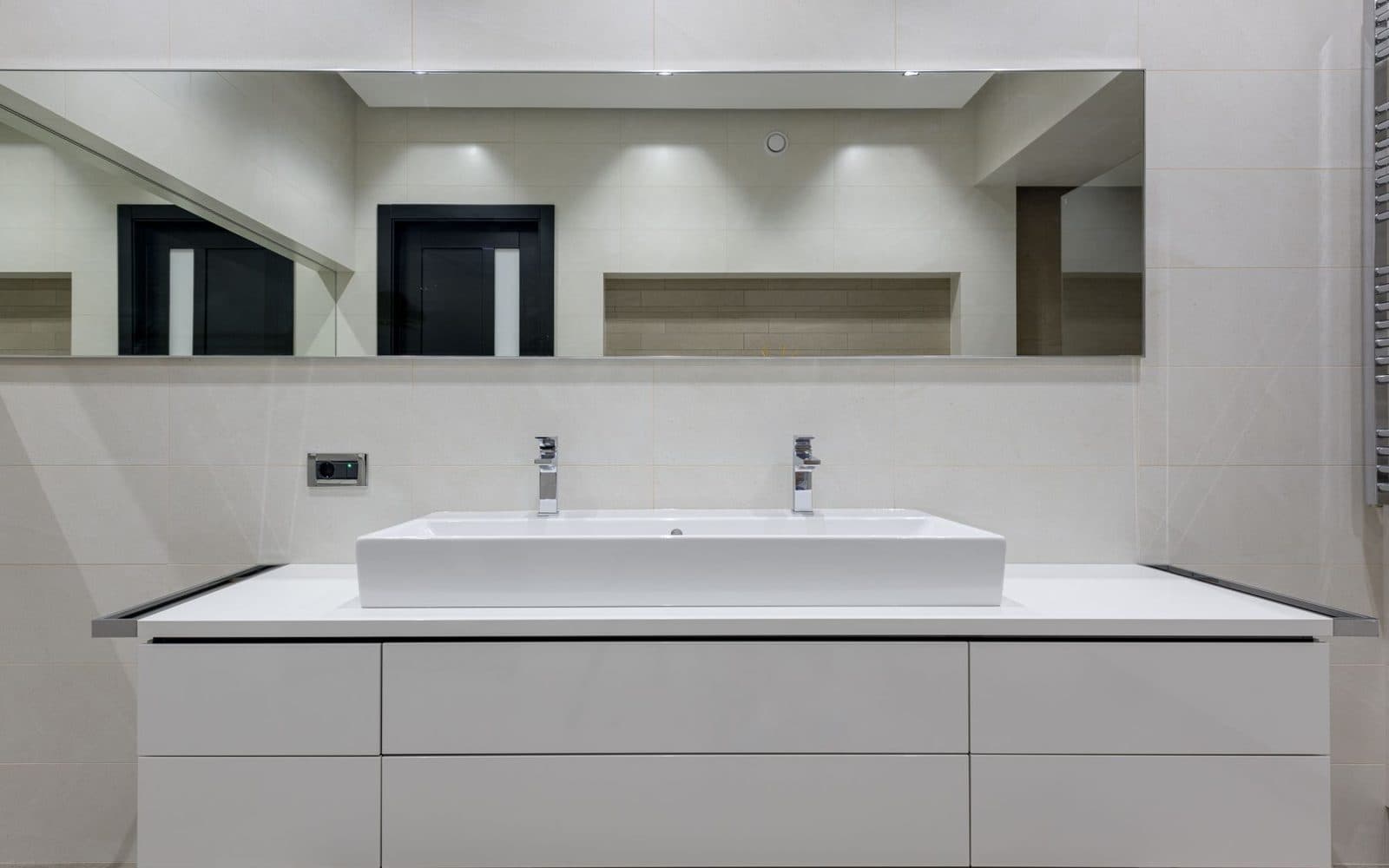 Wide streak-free bathroom mirror above a white floating vanity with a double basin and chrome taps