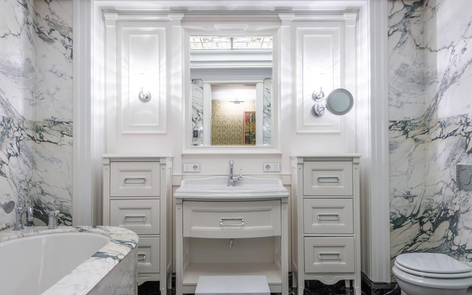 Bright white bathroom with marble walls, a ceramic basin on a white vanity and a freestanding bath