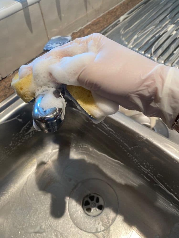 Focus cleaner scrubbing a tap and sink